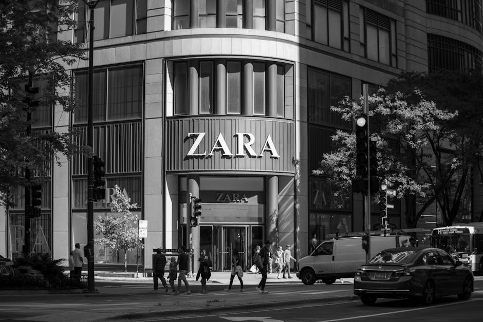 Black and white photo of a Zara storefront in Chicago with pedestrians and cars, depicting urban life.